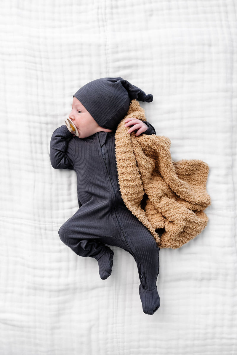 hudson zipper footies newborn boy laying on bed with tan chenille