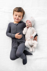 cove zipper footies newborn boy with toddler boy in hudson laying on bed